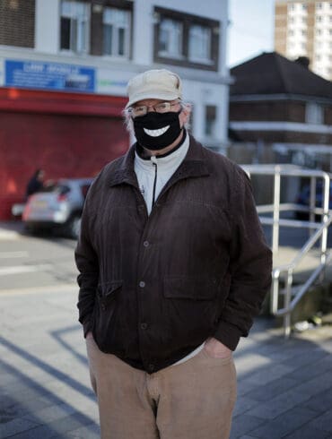 Photo of a man with a Covid mask which features a drawn-on smile design.
